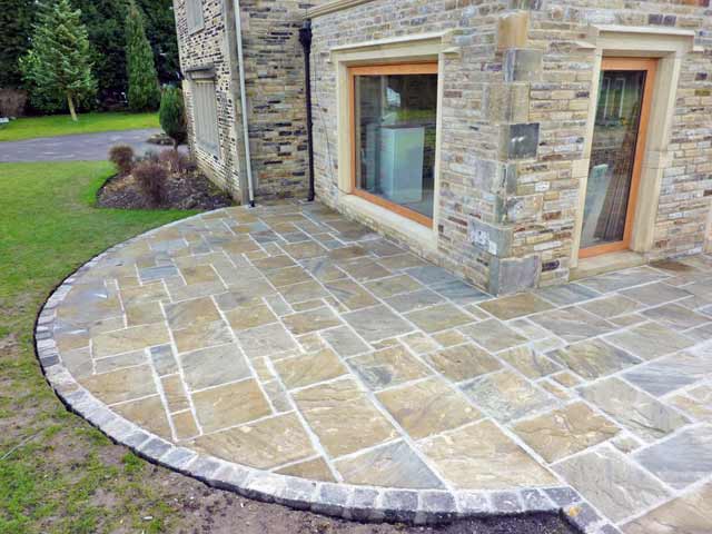 A patio with a mix of sizes and colours of riven yorkstone flags